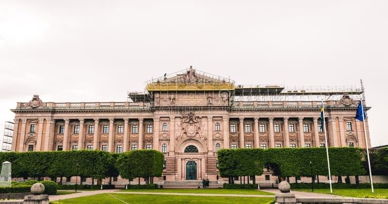 Sveriges riksdagshus med svenska och europeiska flaggor